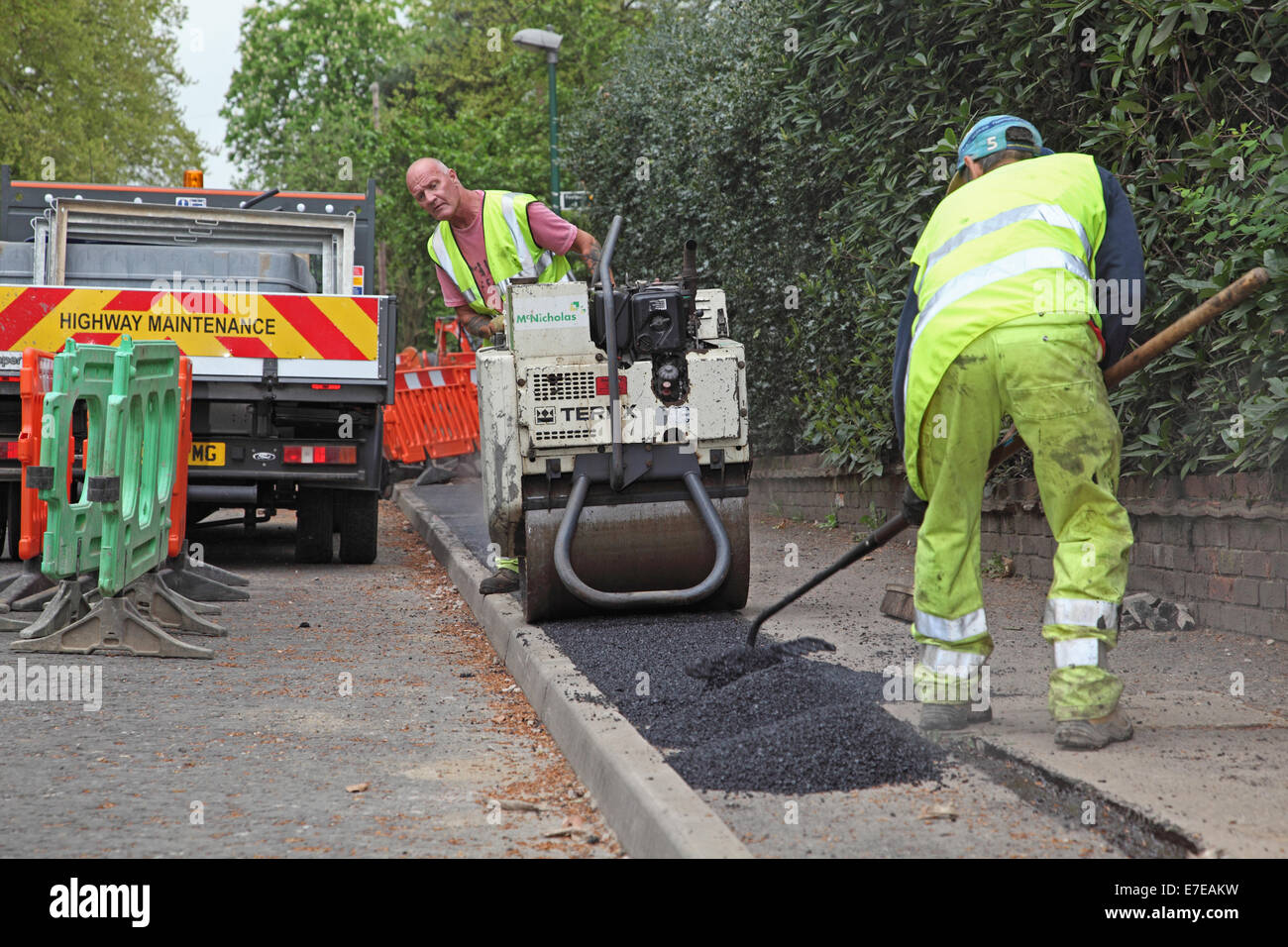 Workmen lay asphalt to a footpath after the installation of new fibre-optic cables for high speed broadband Stock Photo