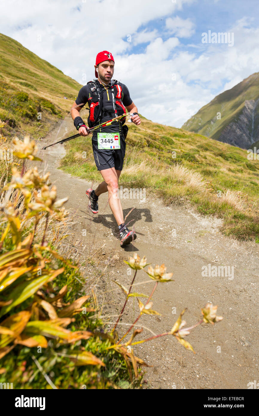 Mountain racers undertaking the Ultra tour du Mont Blanc a mountain marathon with a distance of 166 km, with a total elevation gain of around 9,600 m. The fastest runners will complete it in under 24 hours. Here the racers descend the Grand Col Ferret into Switzerland. Stock Photo