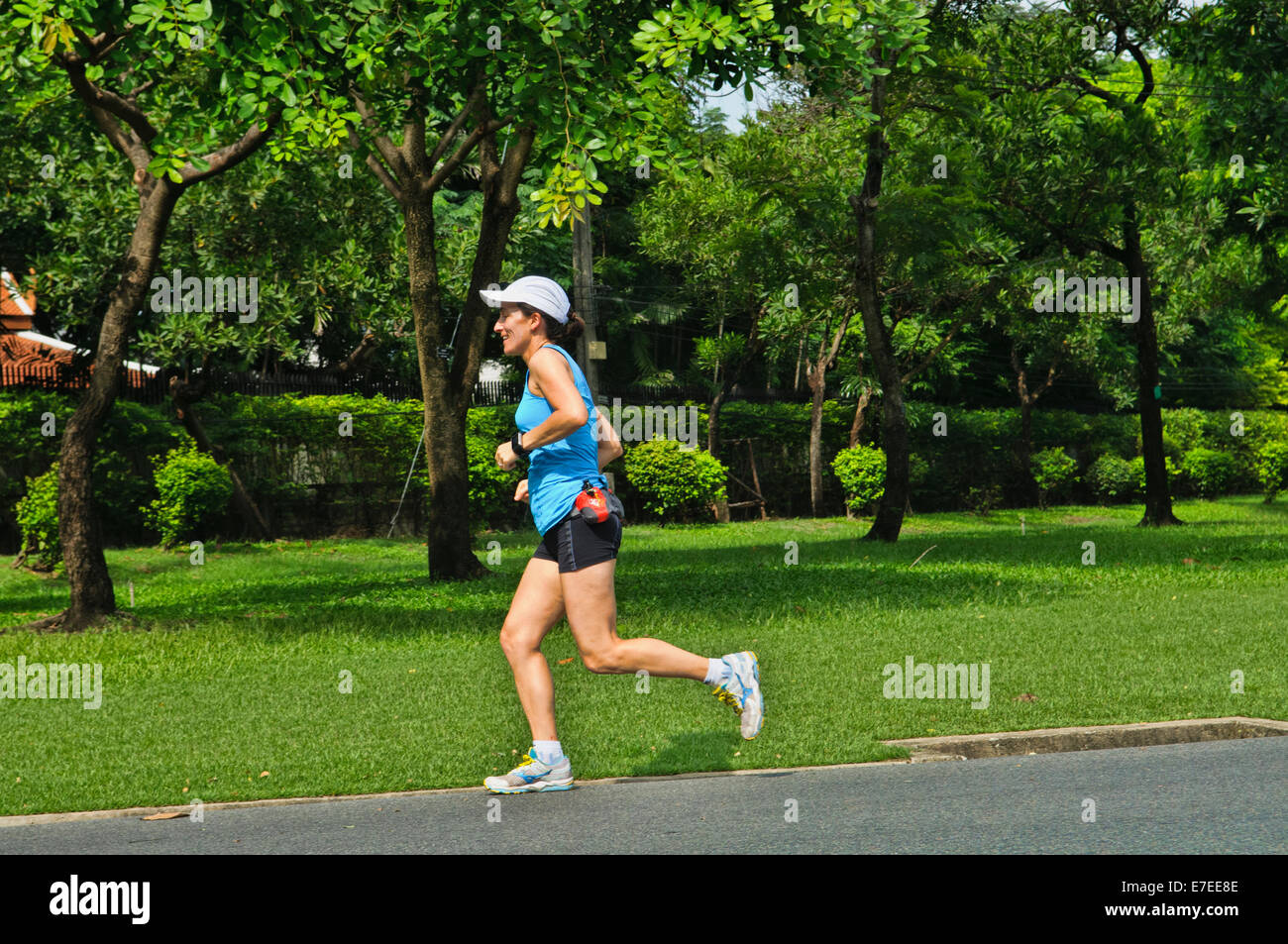 Western woman jogging at a public park in Bangkok, Thailand Stock Photo