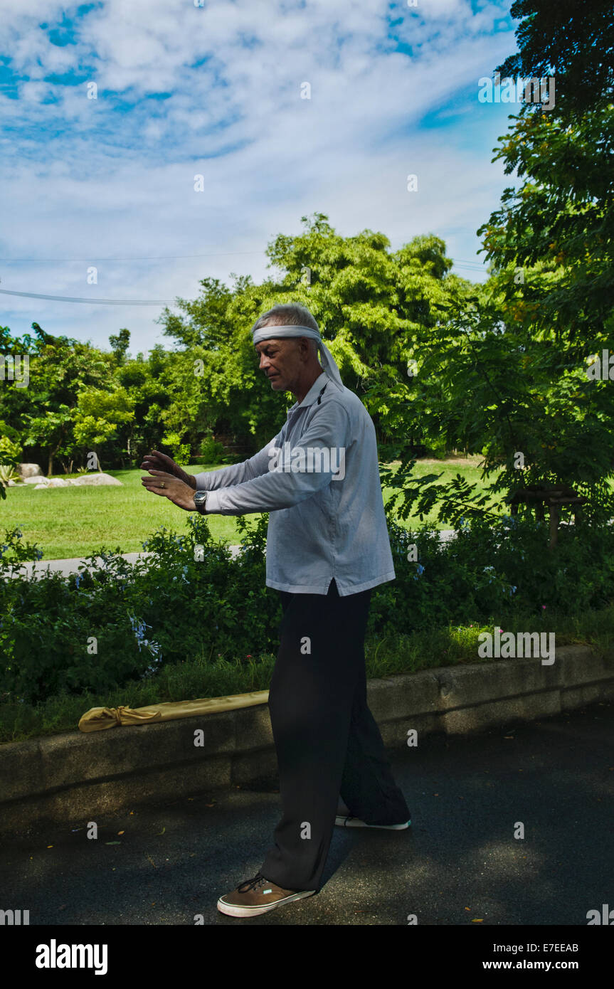 Western man doing Tai Chi on a public park in Bangkok, Thailand Stock Photo