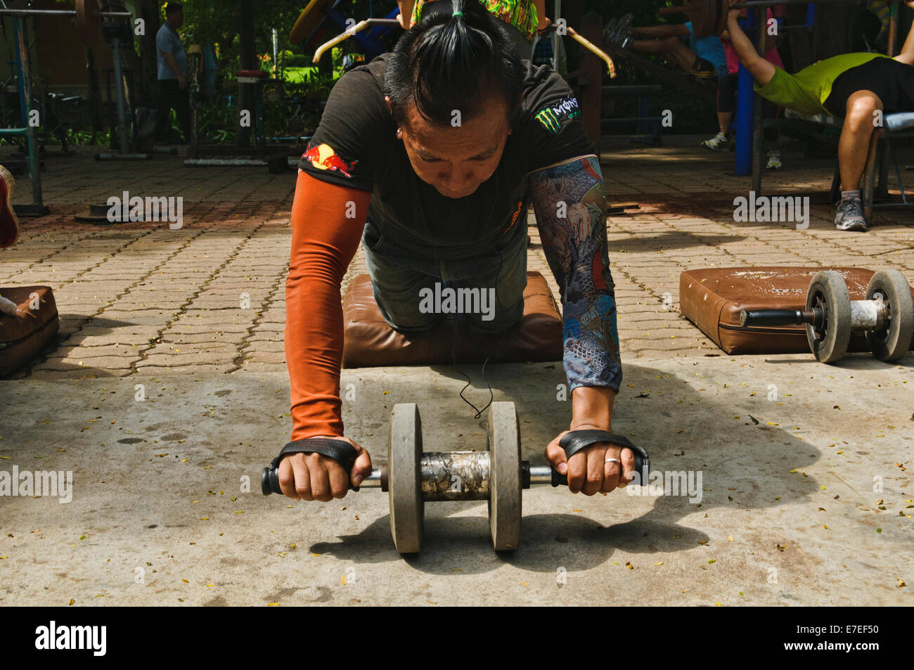 Thai man doing push drop chest exercise at a public park in Bangkok Stock Photo