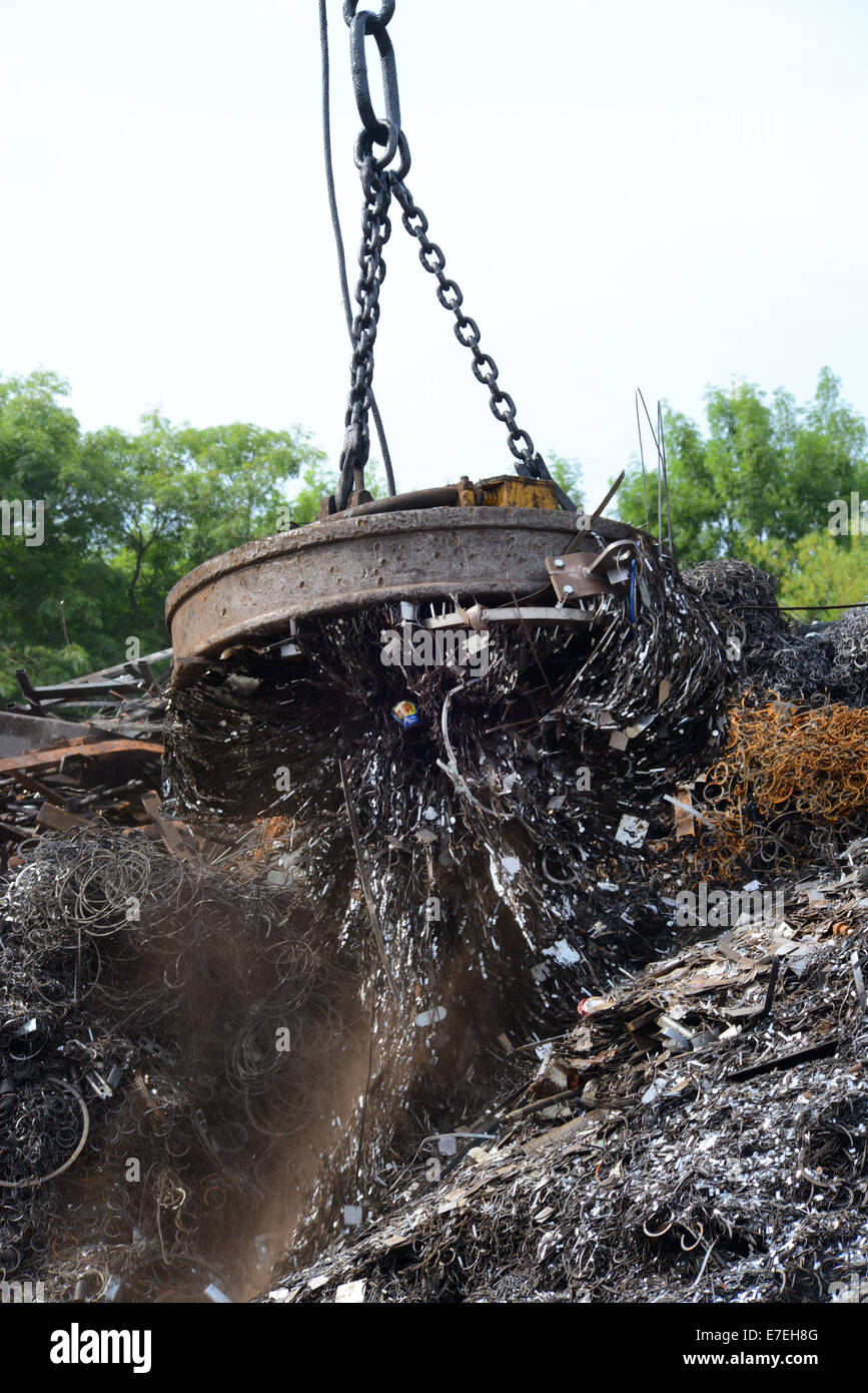 magnetic grab on crane lifting metal at scrapyard uk Stock Photo