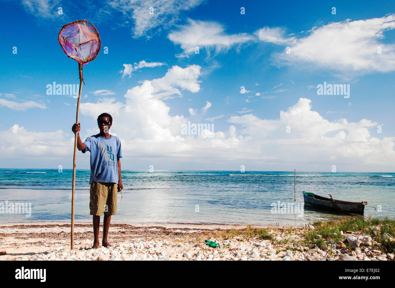 JAMAICA. A skinny man holds a handmade fishing net as he stands on