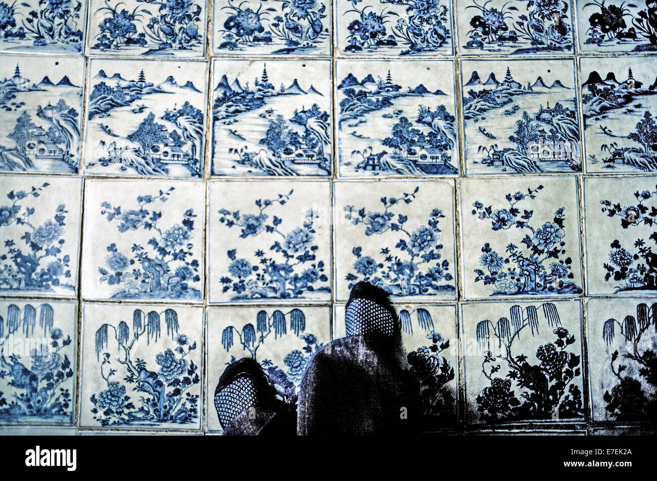 Visitors walk on blue hand-painted ceramic floor tiles brought from China in the 18th Century to the Paradesi Synagogue that was originally built in 1568 for the Jewish community in Kochi (Cochin) in Kerala state, India.  It is one of the oldest functioning synagogues in the world and welcomes visitors to view its other historical treasures that include a teak ark with scrolls of the Torah and gold and silver crowns, the brass-railed pulpit, and glass chandeliers and lamps imported in the 1800s from Europe. Visitors are expected to enter the synagogue without footwear. Photographed in 1974. Stock Photo