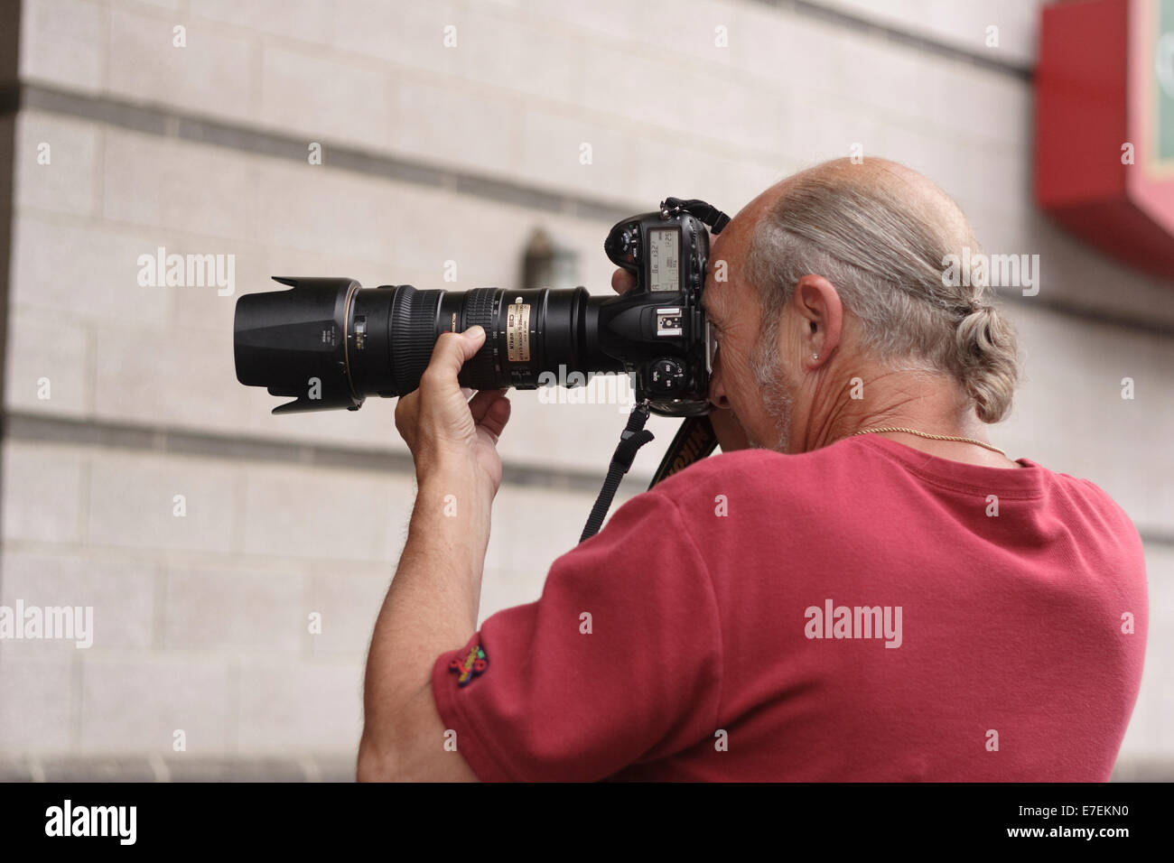 Street photographer taking photograph with Nikon 35mm camera and zoom