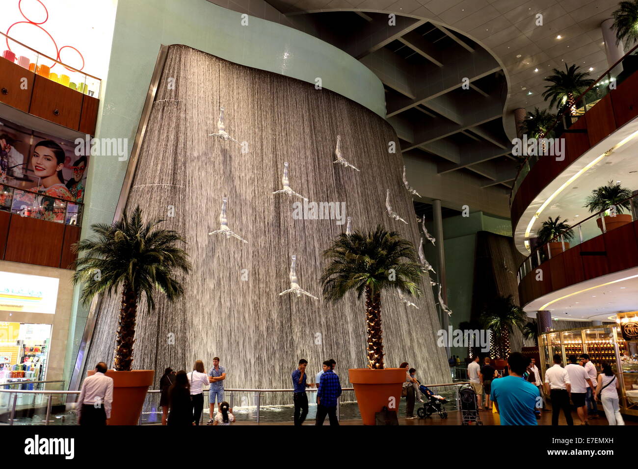 Shops, shoppers, department stores, palms and waterfall with statues of