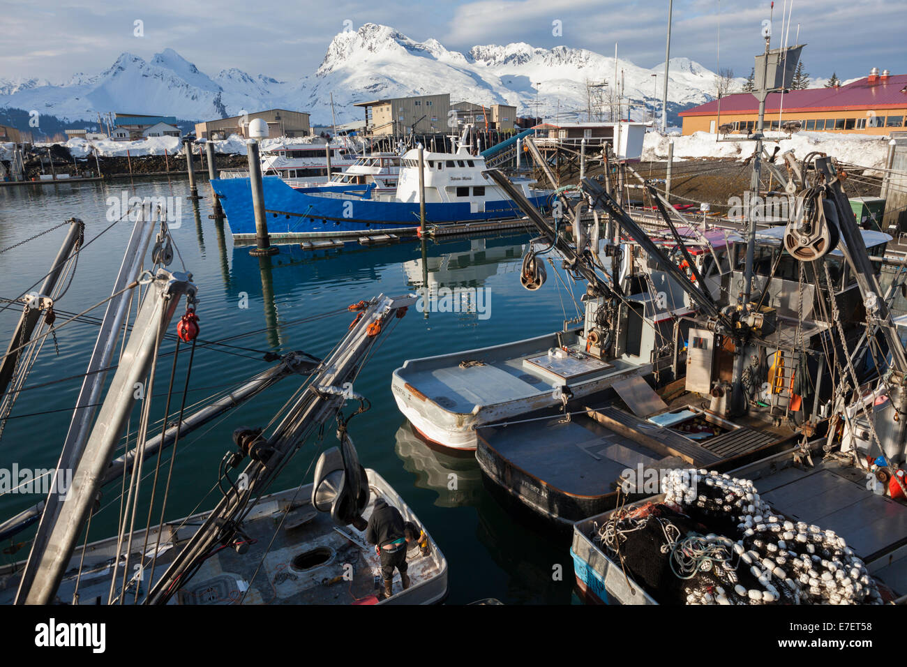 Fishing boats moored at the harbor in Valdez, Alaska. Peaks of the Chugach Mountains are visible across the fjord. Stock Photo