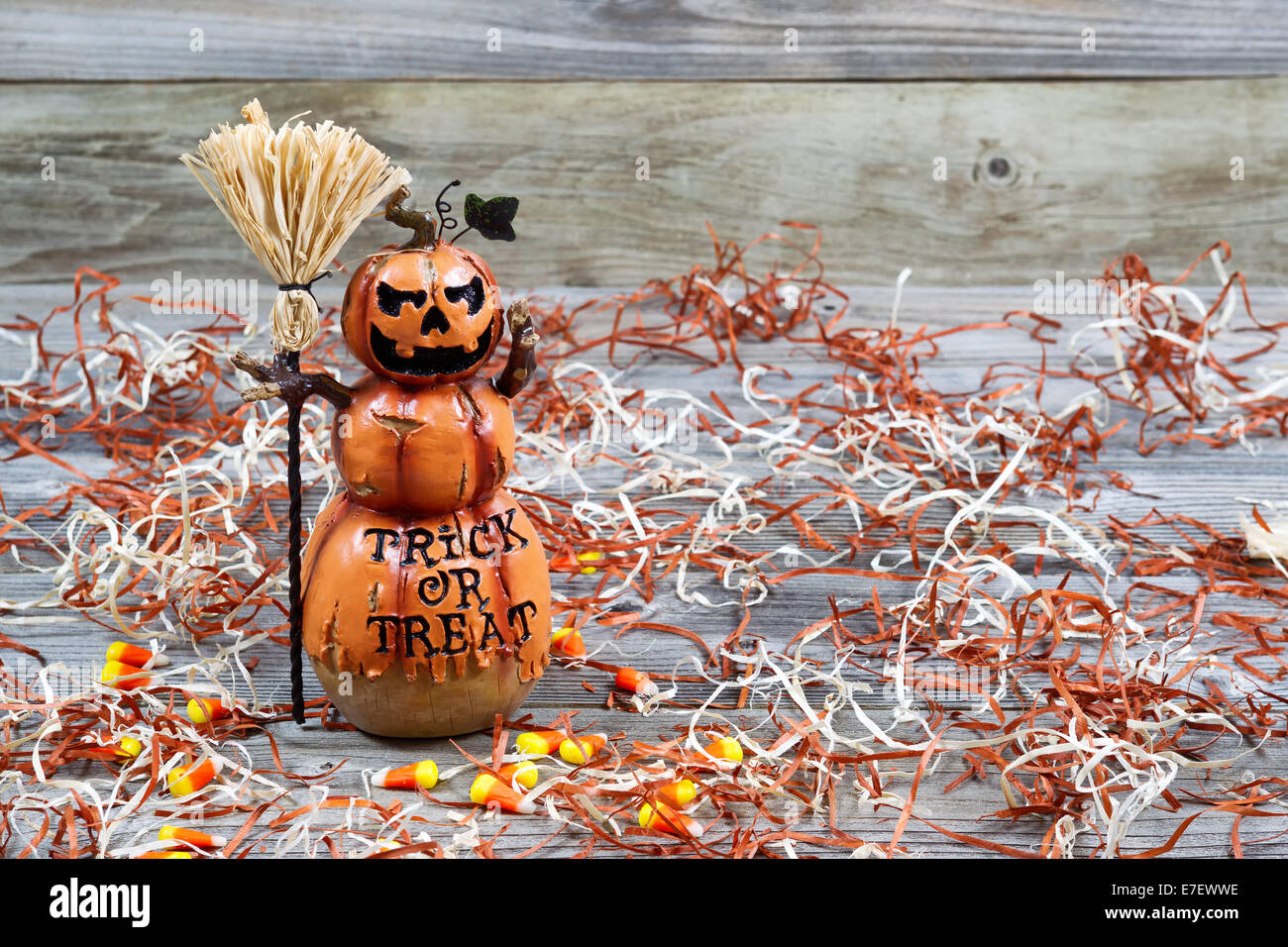 Horizontal image of a scary orange pumpkin figure holding straw broom placed on rustic wooden boards Stock Photo