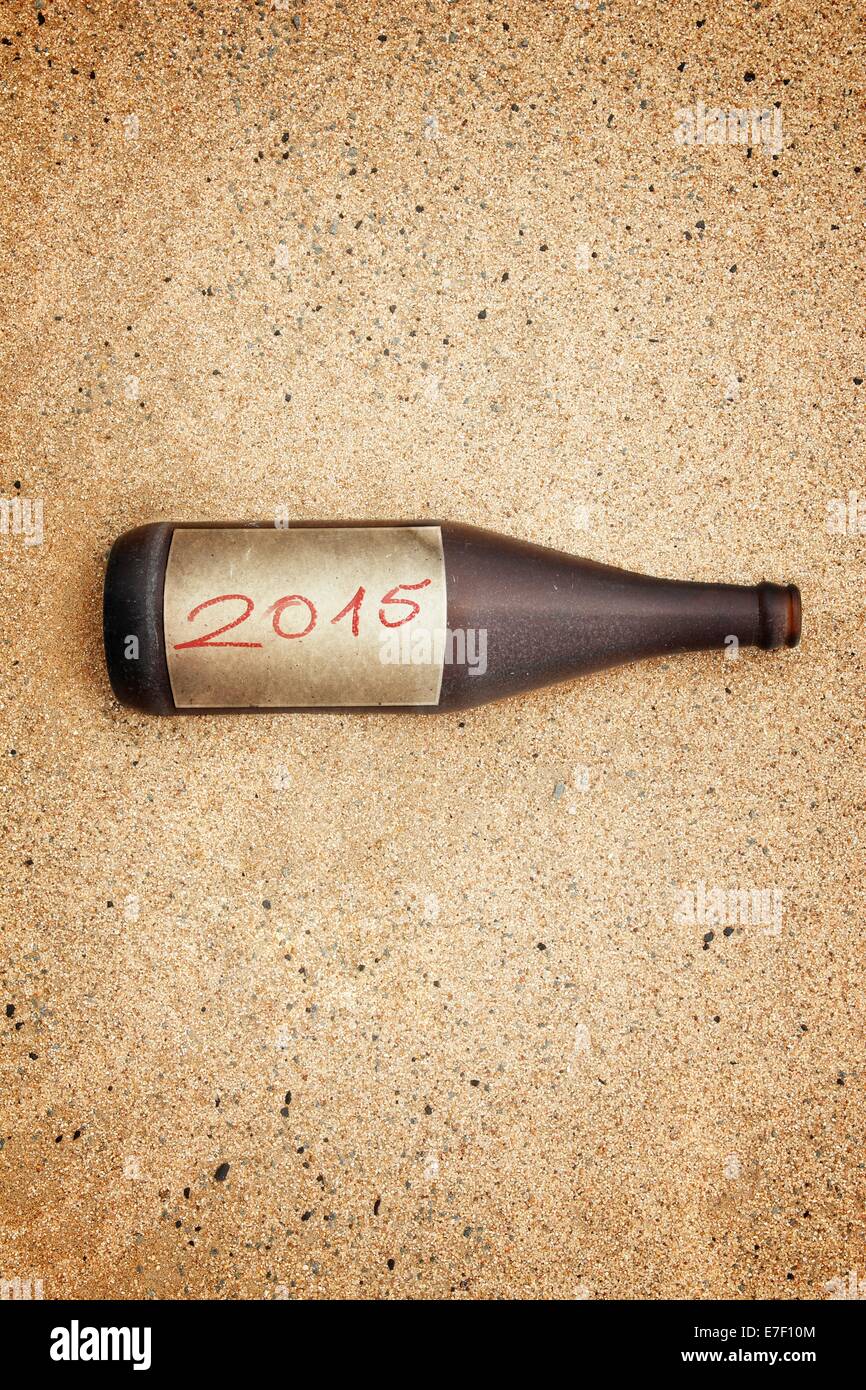 Vintage version of washed out bottle with 2015  label on gravel beach. Stock Photo