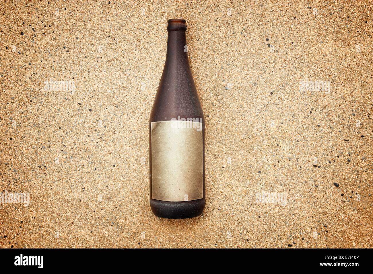 Vintage version of washed out bottle with empty label on gravel beach. Stock Photo