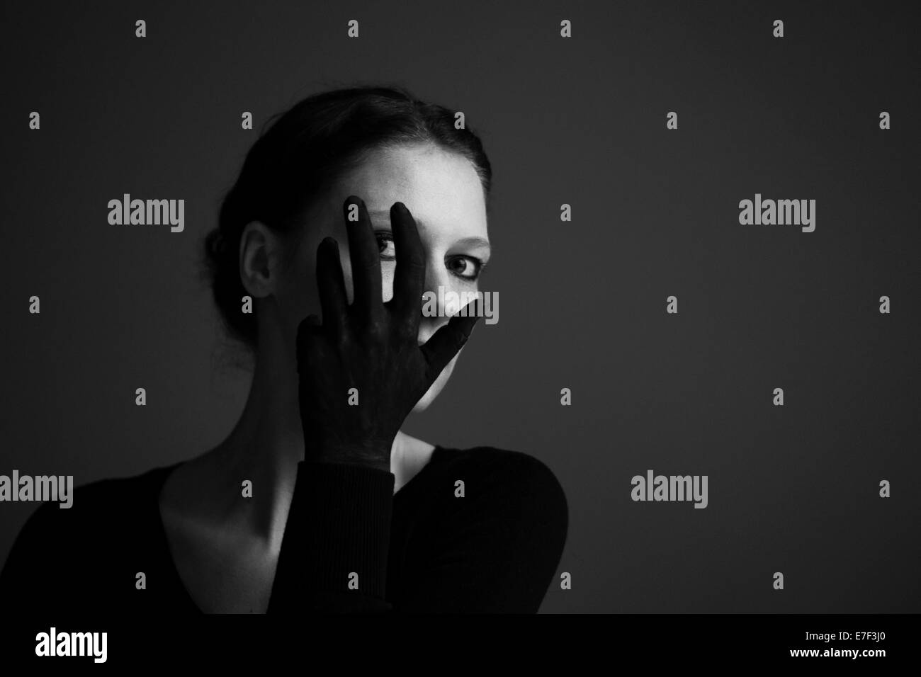Woman holding her hand with a black glove in front of her face Stock Photo