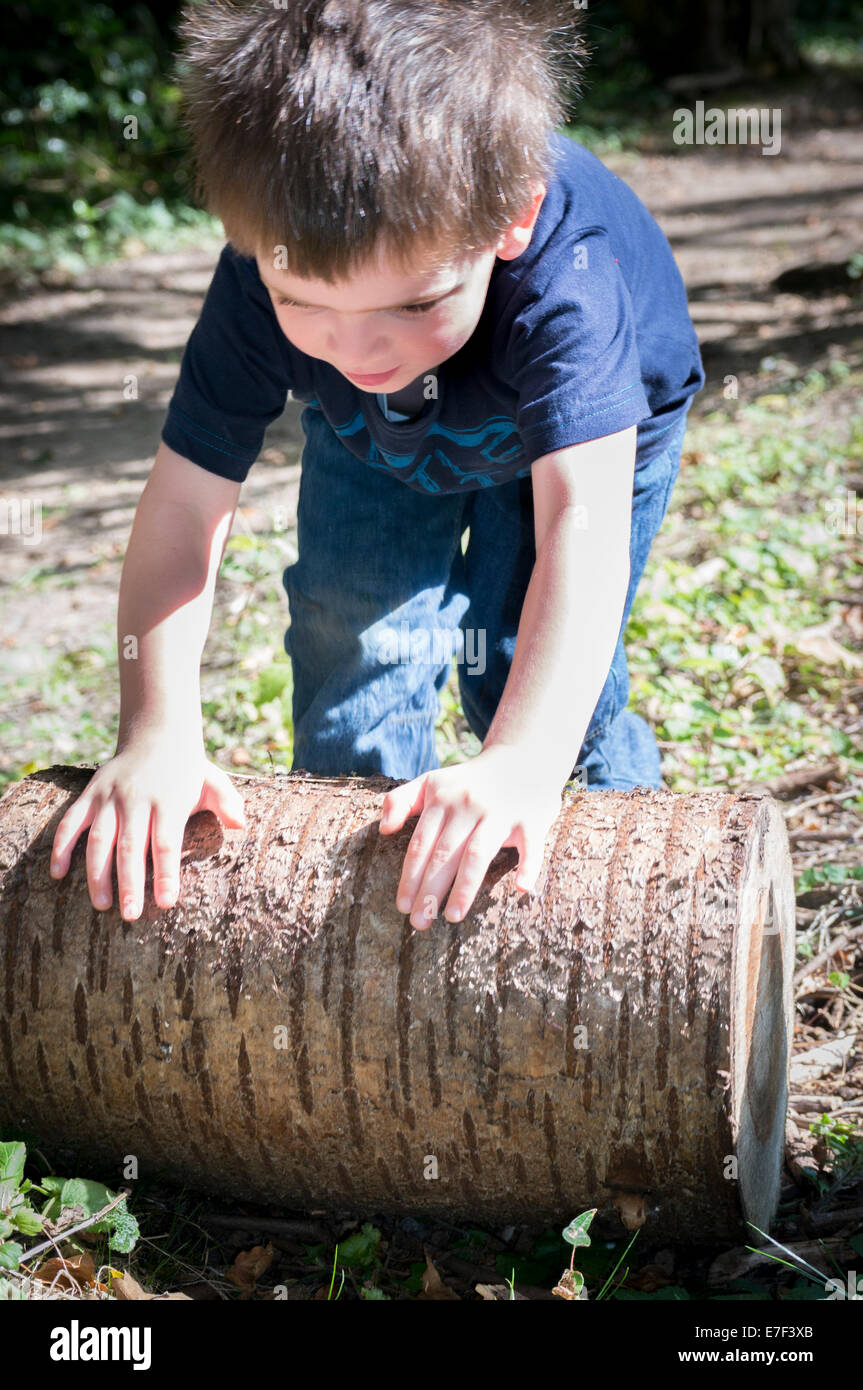 A small boy rolling a log Stock Photo