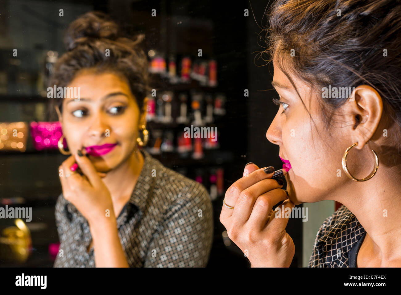 Young woman applying lipstick, in a make-up shop, Mumbai, Maharashtra, India Stock Photo