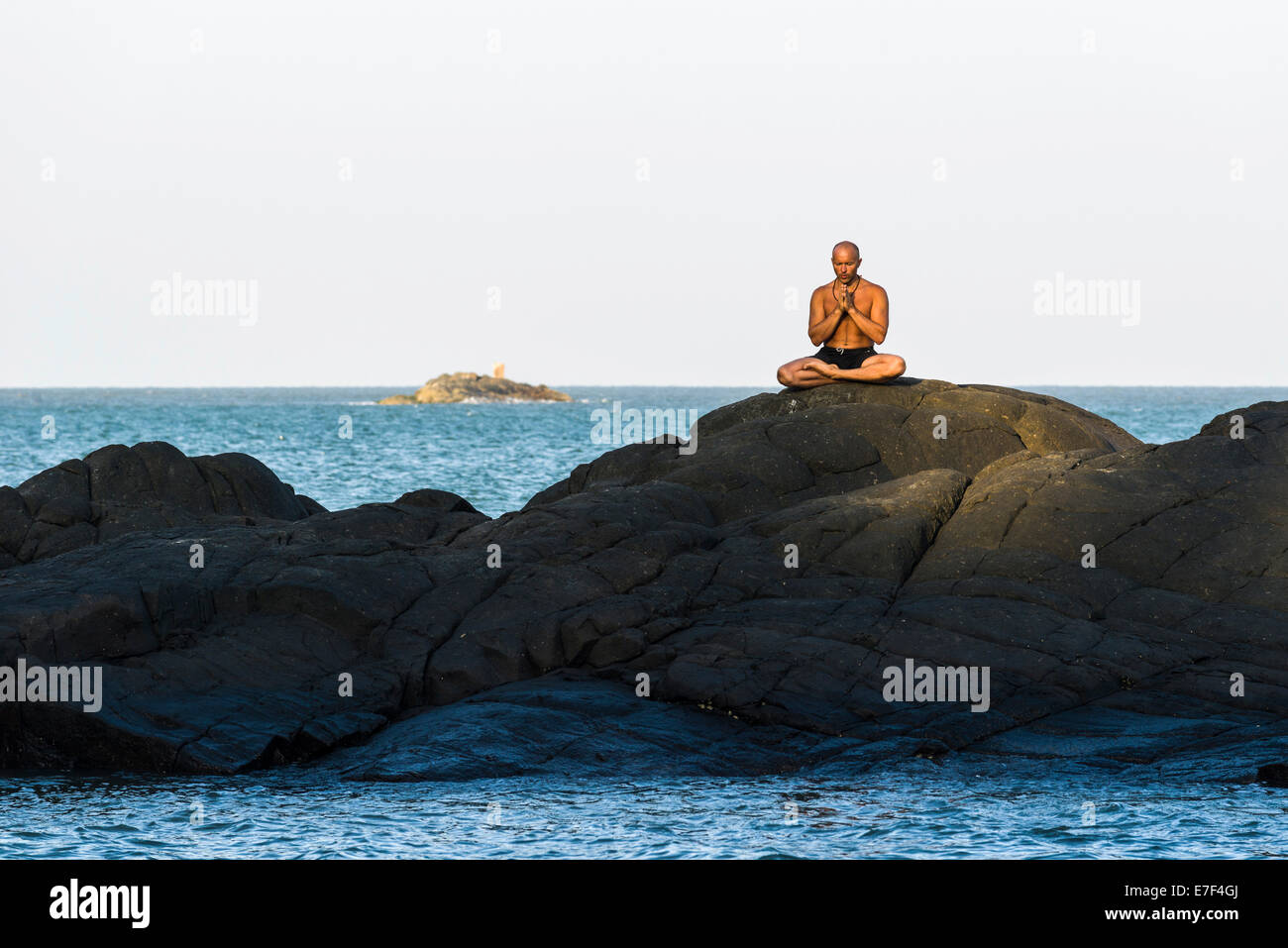 A man is meditating, practicing yoga on a rock, Kudle Beach, Gokarna, Karnataka, India Stock Photo