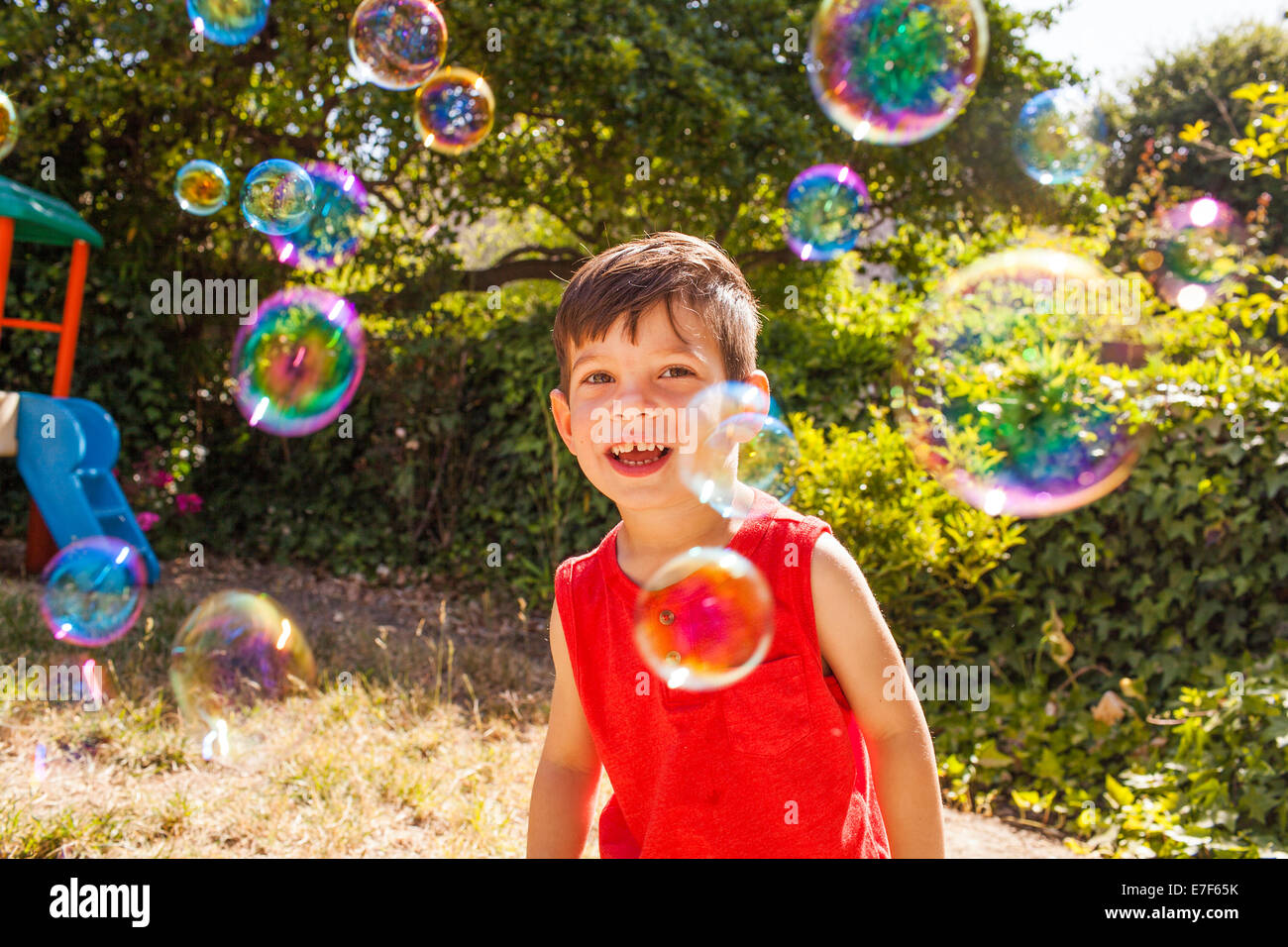 Mixed race boy playing with bubbles in backyard Stock Photo