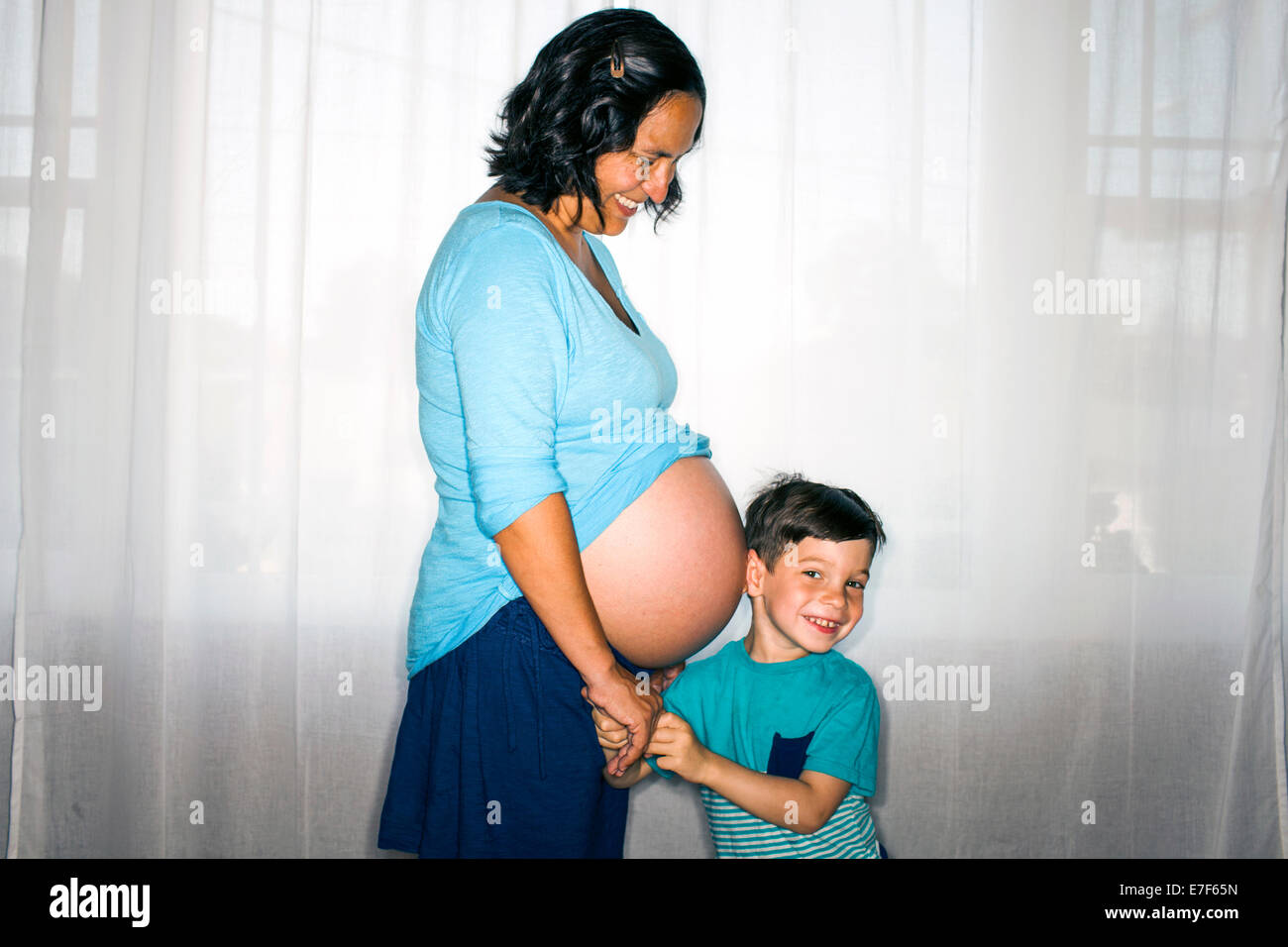 Boy listening to mother's pregnant belly Stock Photo