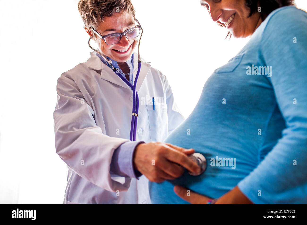 Doctor listening to womanÕs pregnant belly Stock Photo