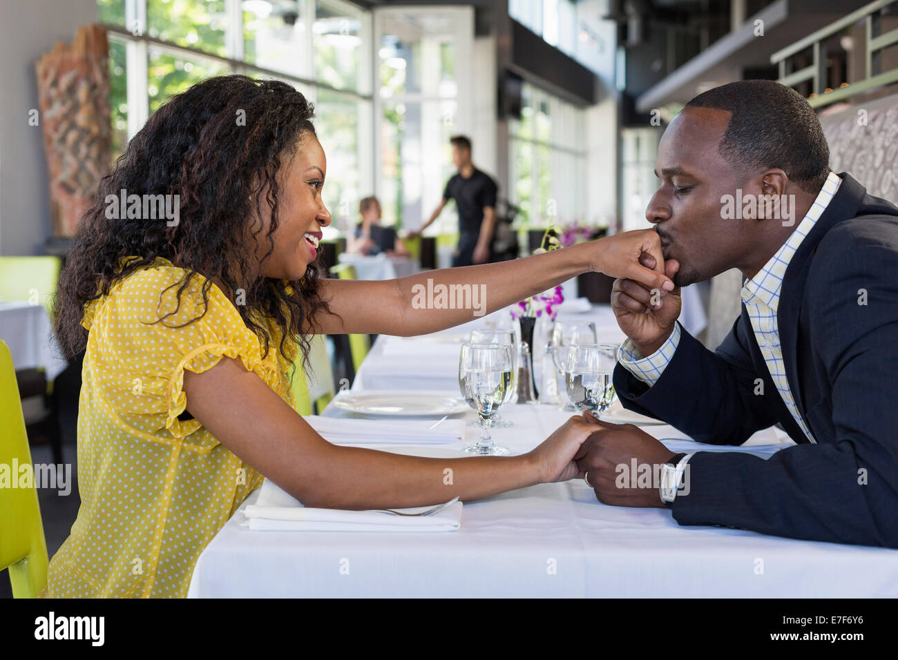 African American man kissing girlfriend's hand in restaurant Stock Photo