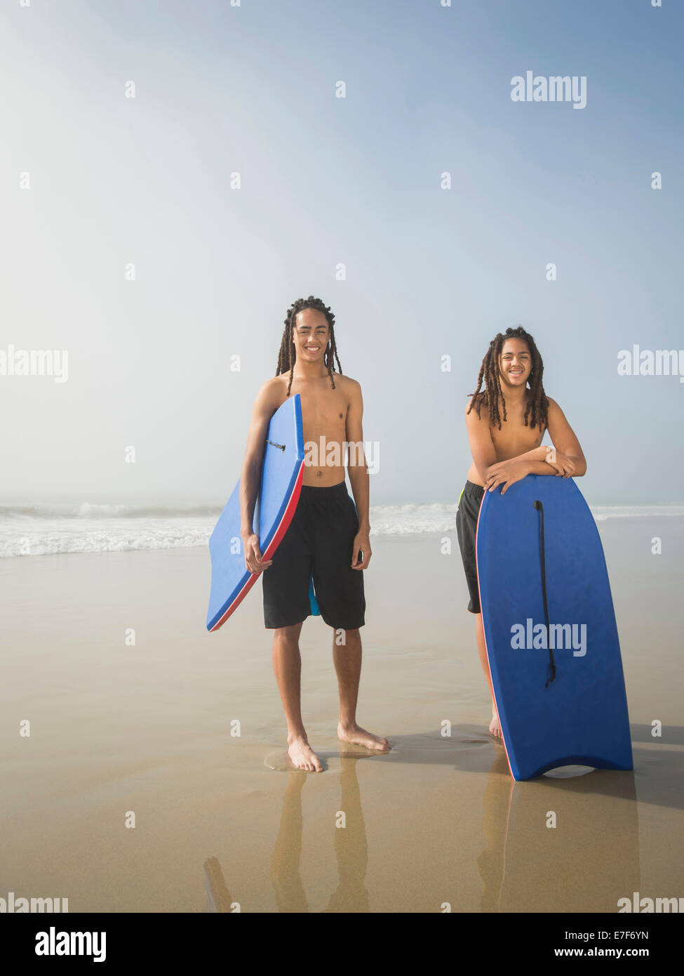 Black teenage boys with boogie boards on beach Stock Photo