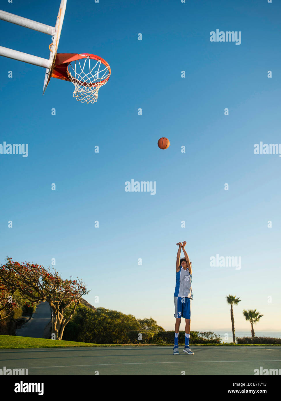 Black teenage boy shooting basketball on court Stock Photo