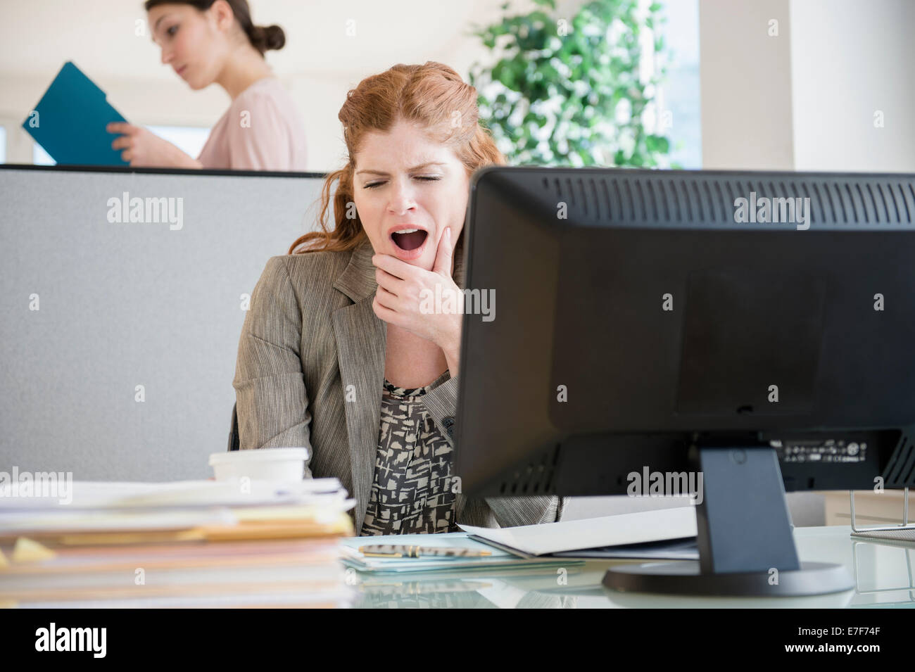 Caucasian businesswoman yawning at desk Stock Photo