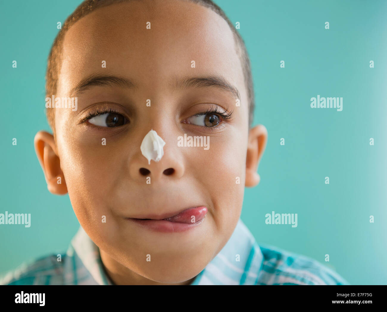 Mixed race boy with icing on nose Stock Photo