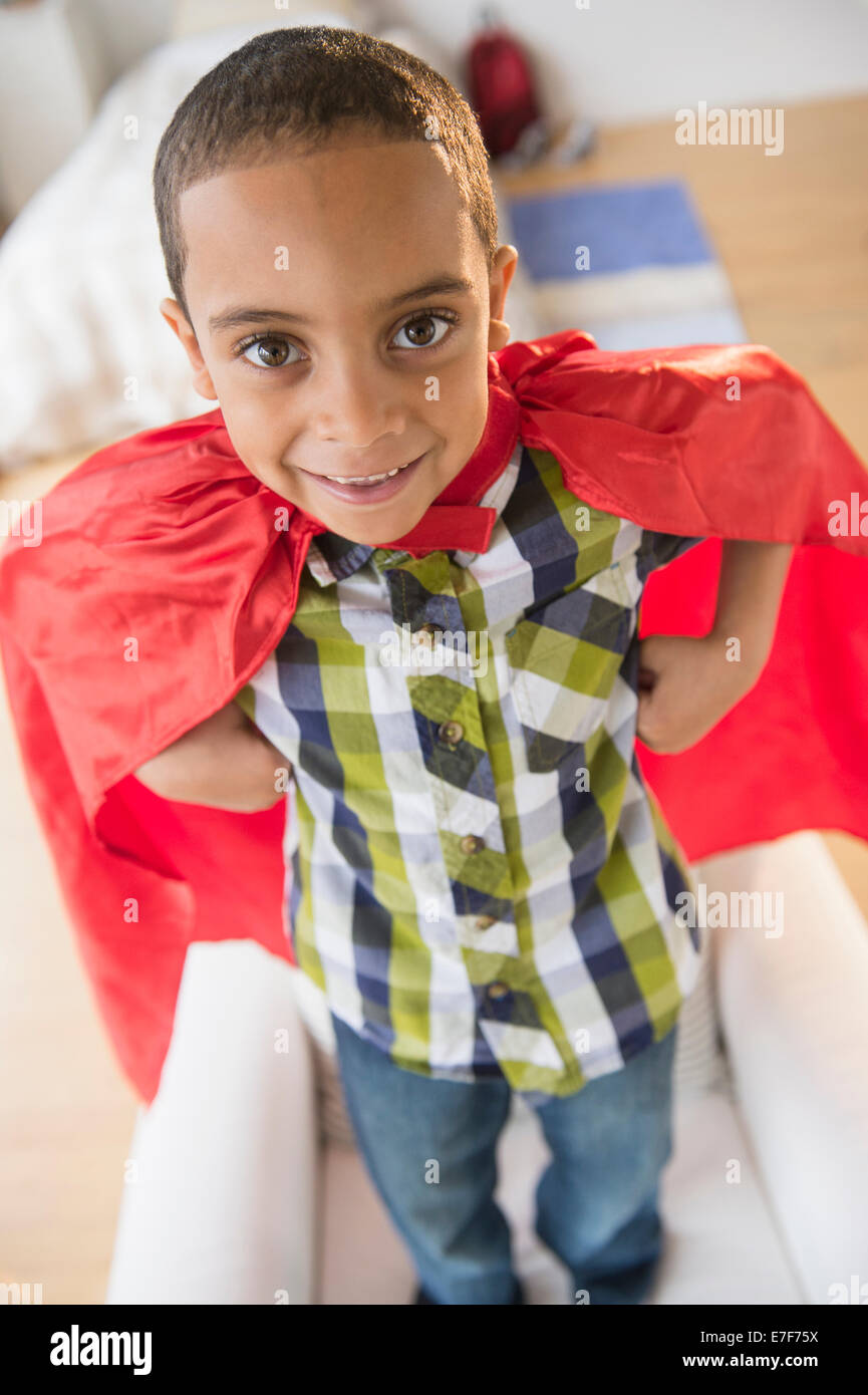 Mixed race boy wearing cape on armchair Stock Photo