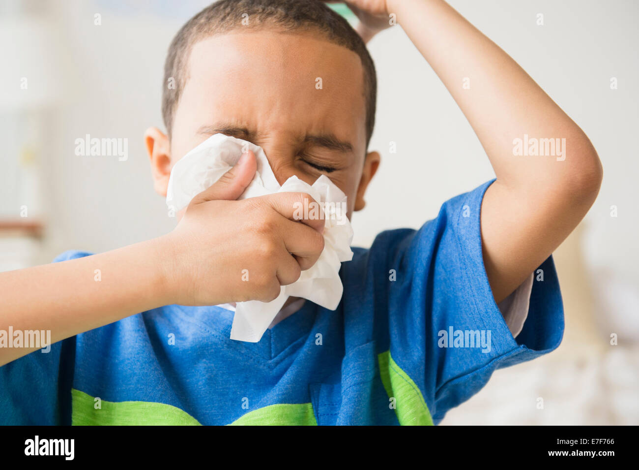 Mixed race boy blowing his nose Stock Photo