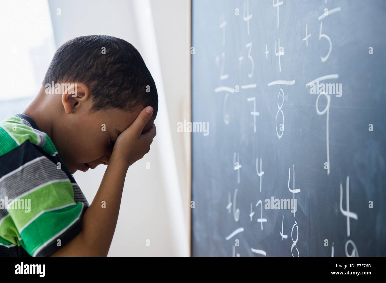Mixed race boy doing math problems at board in class Stock Photo