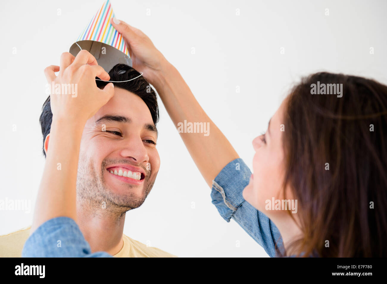 Woman putting party hat on boyfriend Stock Photo