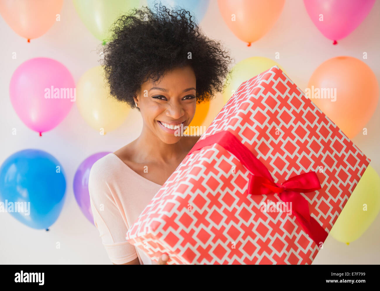 African American woman holding wrapped gift at birthday party Stock Photo