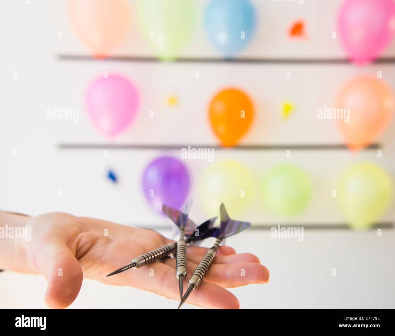 African American woman holding darts by wall of balloons Stock Photo