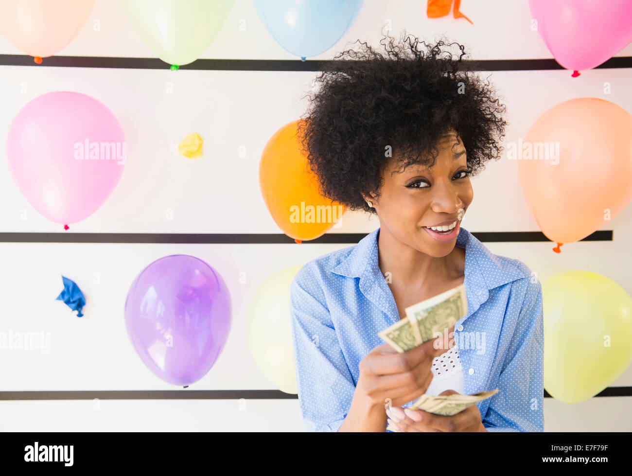 African American woman counting money at balloon wall Stock Photo