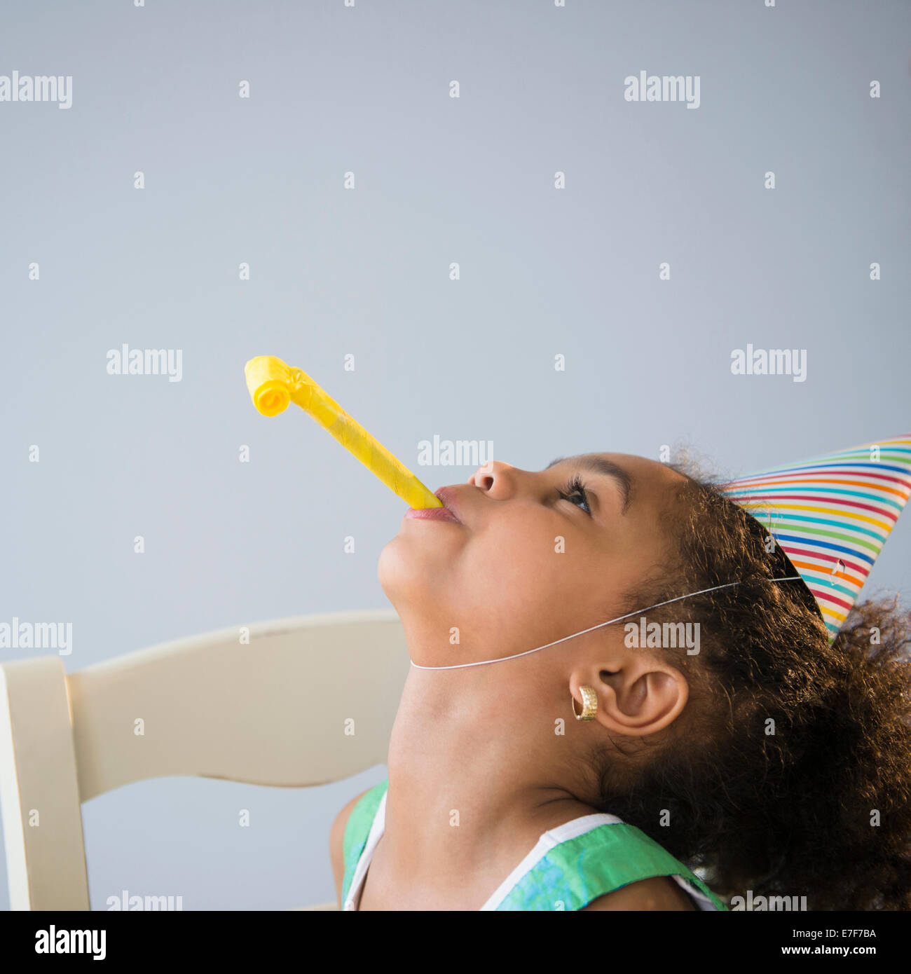 African American girl blowing noisemaker at birthday party Stock Photo