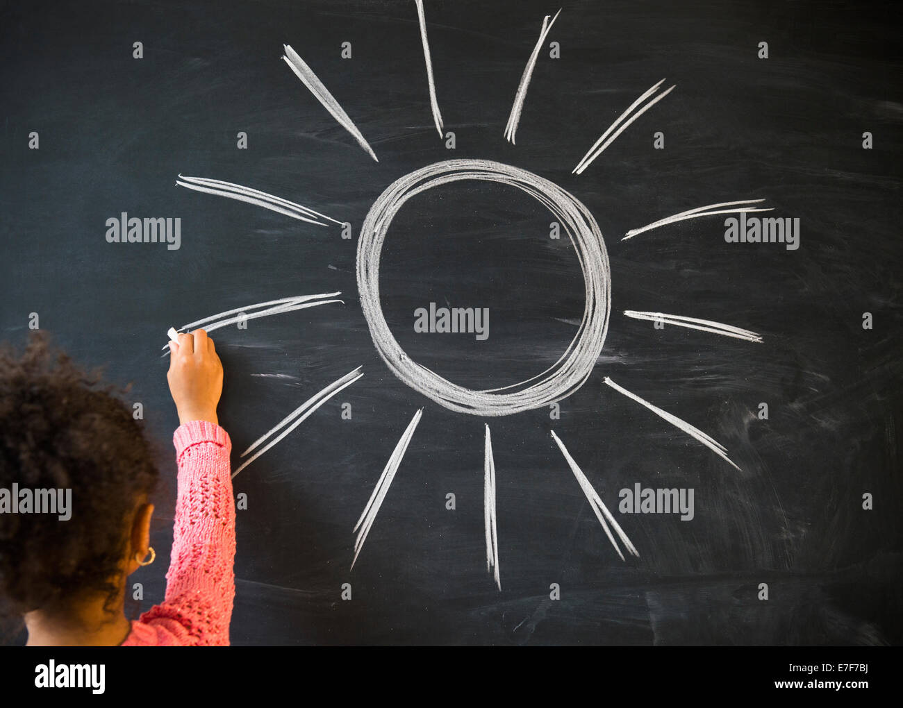 African American girl drawing sun on board in classroom Stock Photo