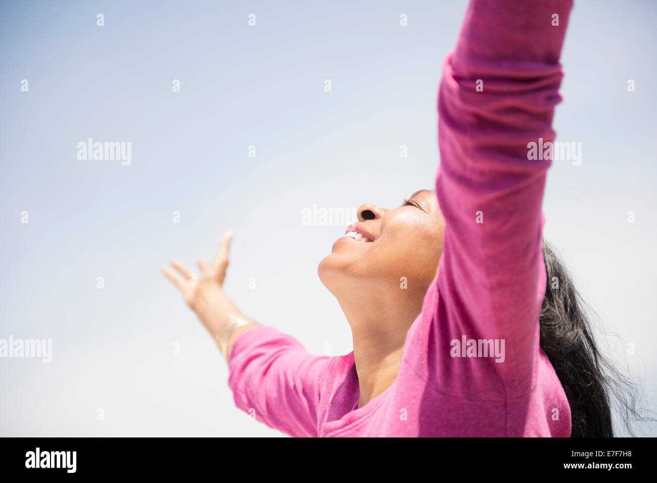 Mixed race woman with arms outstretched outdoors Stock Photo