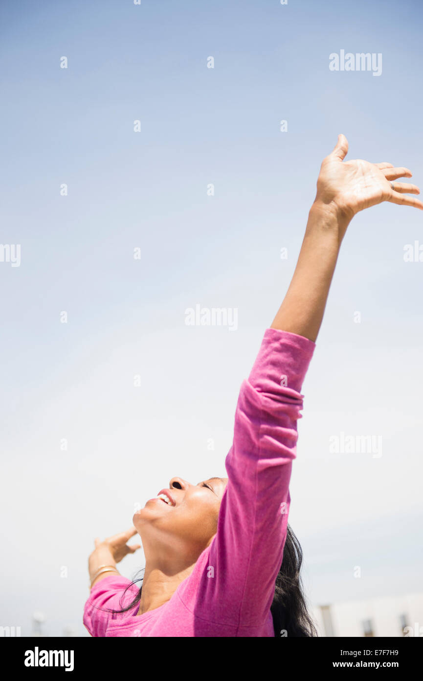 Mixed race woman with arms outstretched outdoors Stock Photo