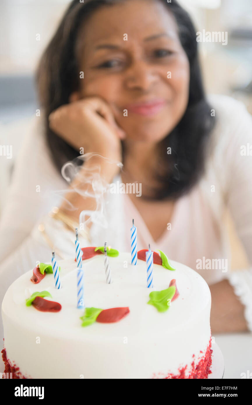 Mixed race woman blowing out birthday candles on cake Stock Photo