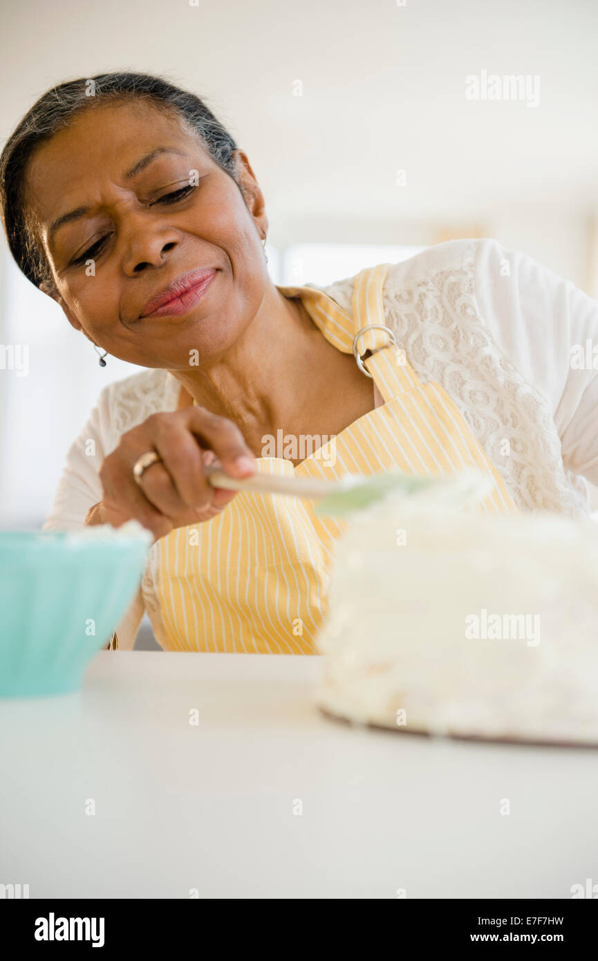 Mixed race woman frosting cake in kitchen Stock Photo