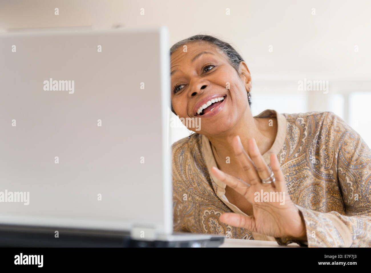 Mixed race woman using laptop at table Stock Photo