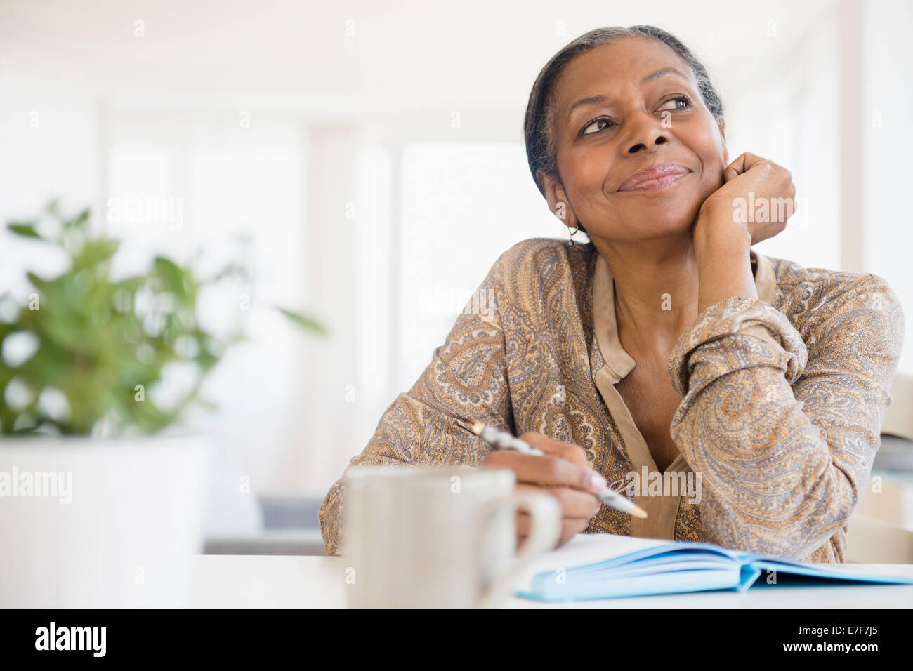 Mixed race woman writing at desk Stock Photo