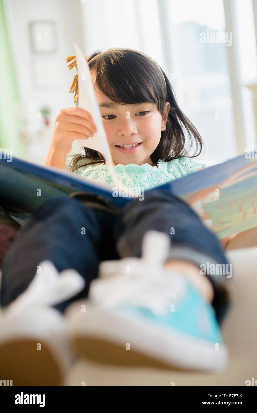 Filipino girl reading book on sofa Stock Photo