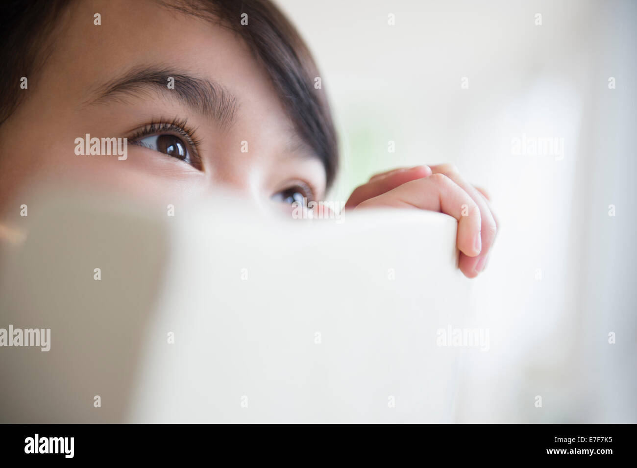 Close up of Filipino girl peering over chair back Stock Photo