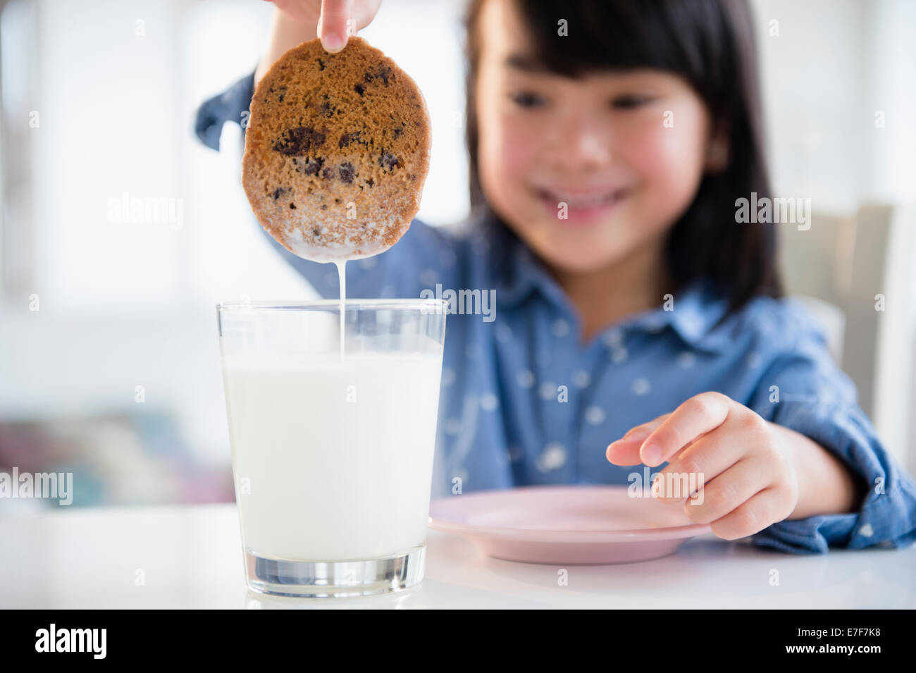 Filipino girl dunking cookie in milk Stock Photo