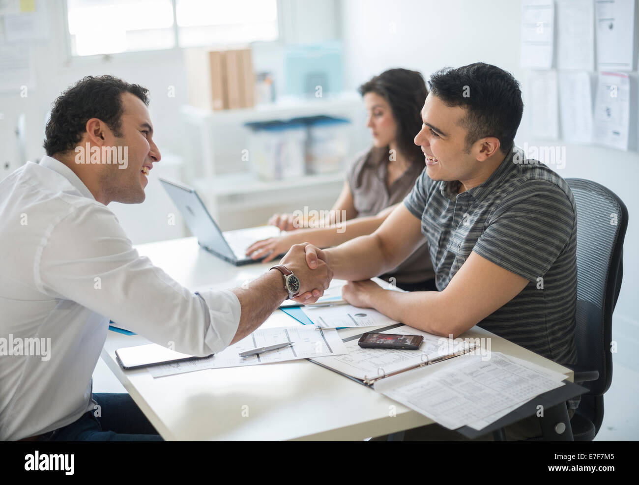Hispanic businessmen shaking hands in office Stock Photo