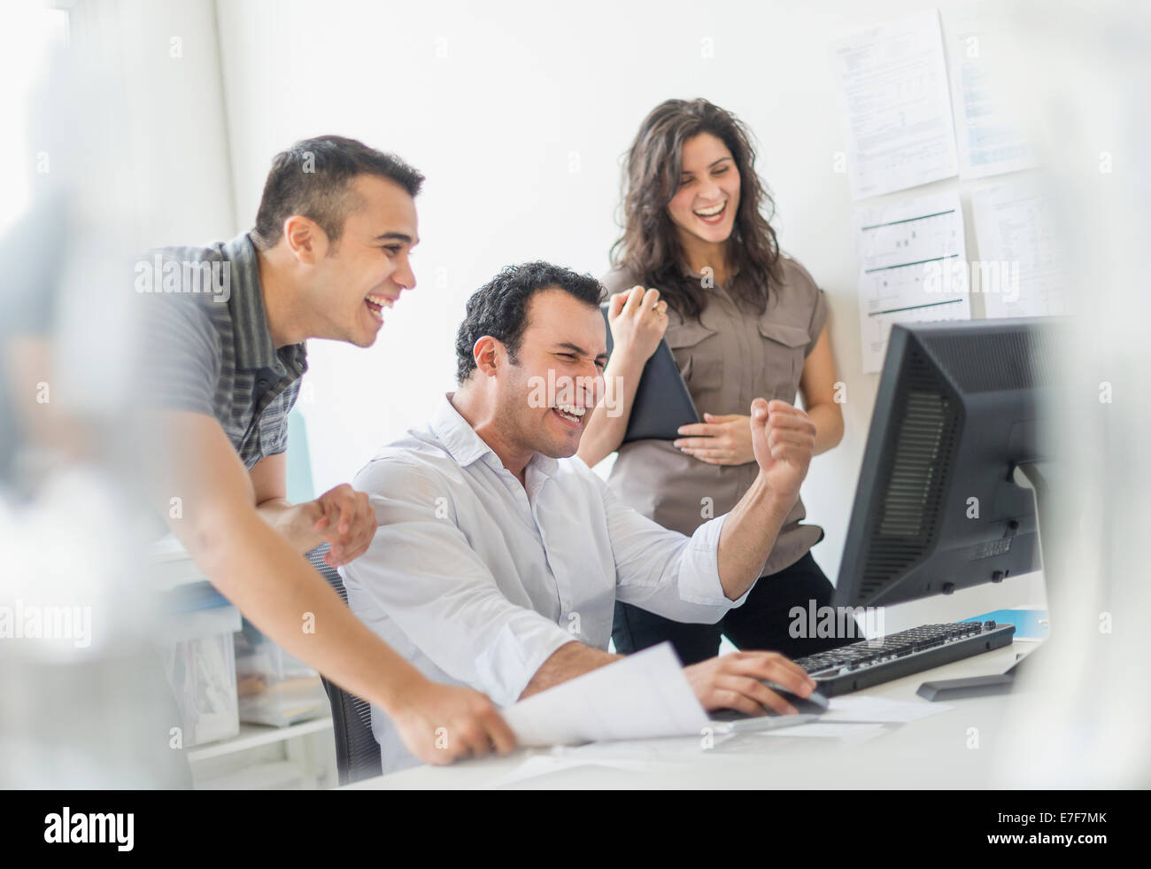 Hispanic business people cheering together in office Stock Photo