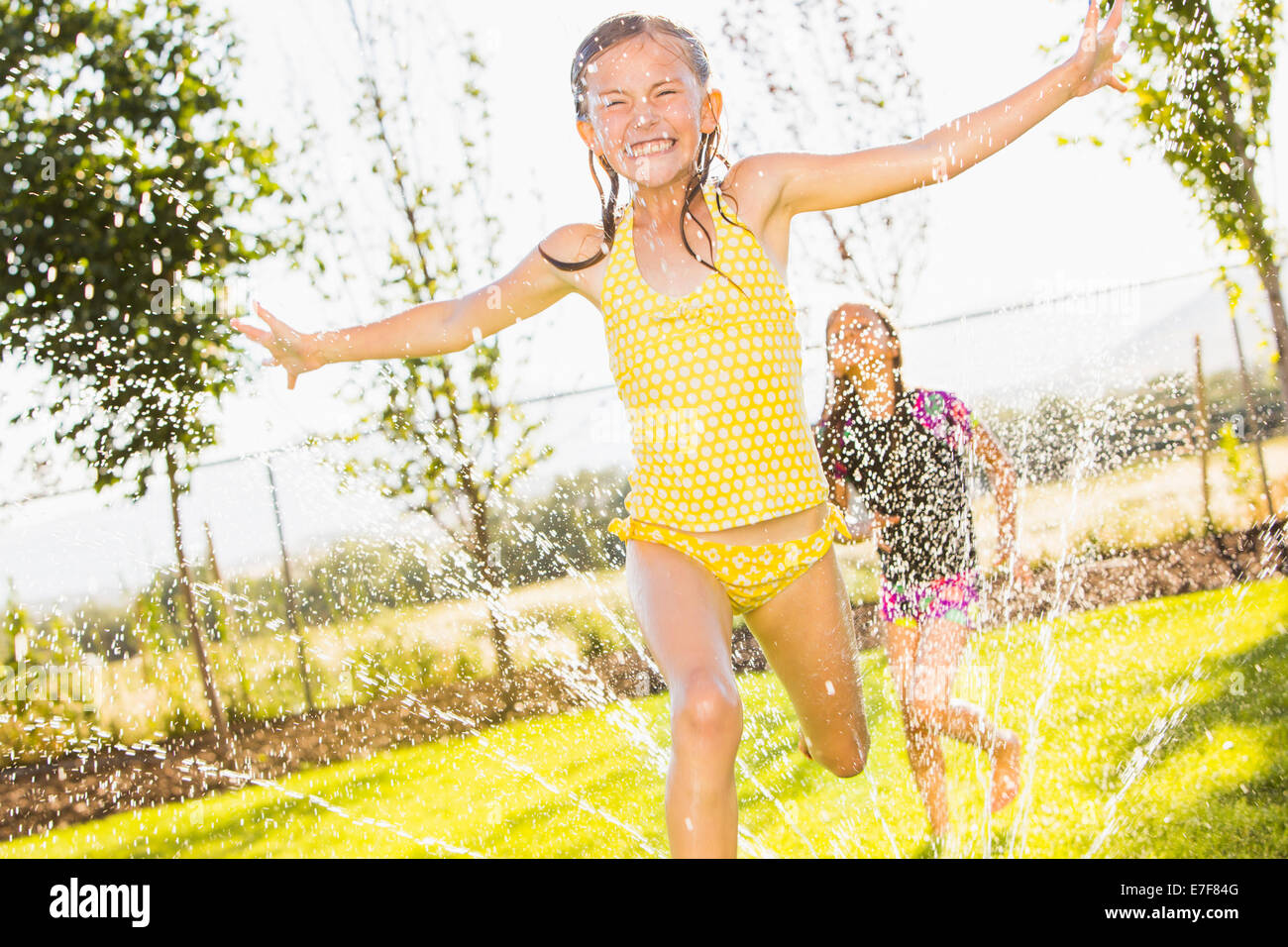 Caucasian girls playing in sprinkler hi res stock photography and