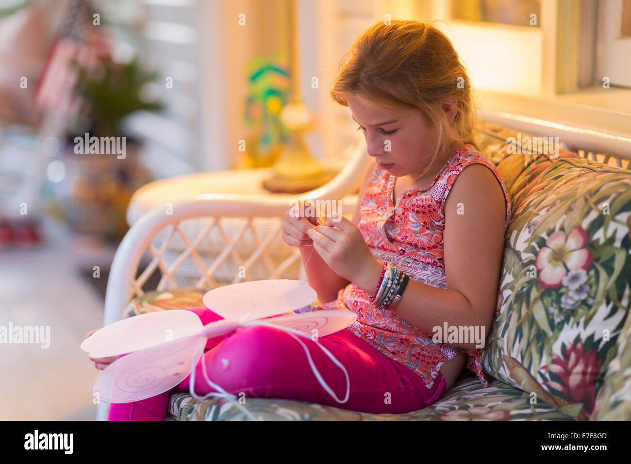Caucasian girl sewing fairy wings on sofa Stock Photo