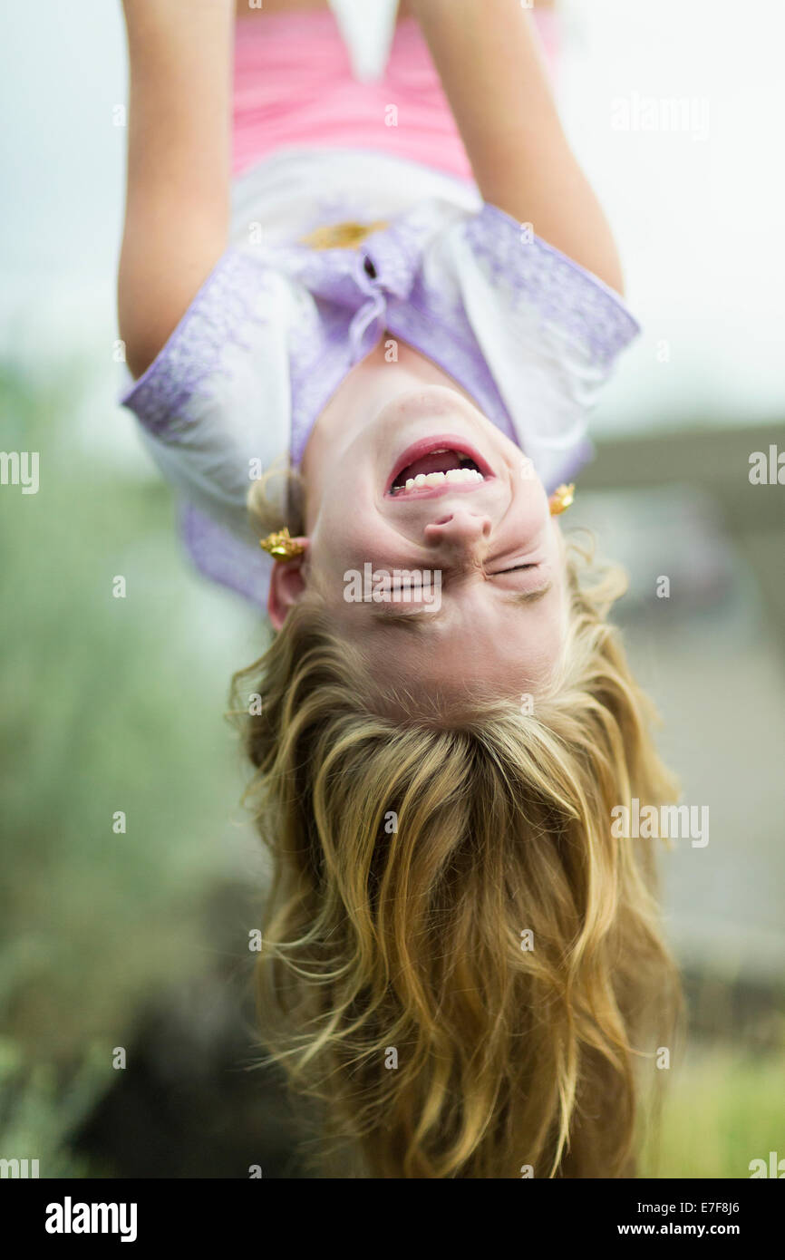 Caucasian girl hanging upside down outdoors Stock Photo
