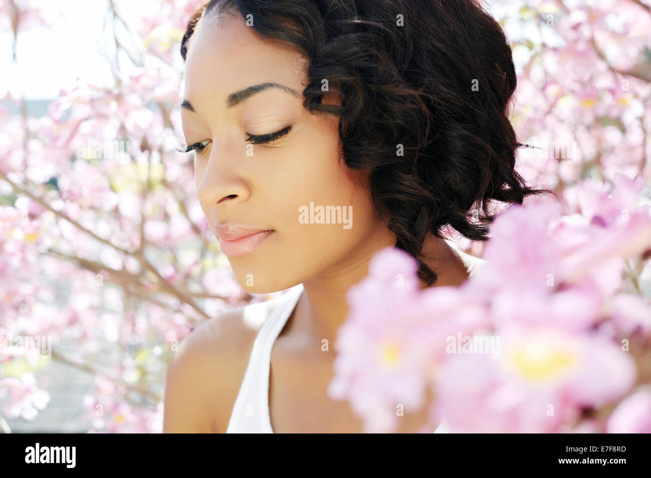 African American woman standing by flowering tree Stock Photo
